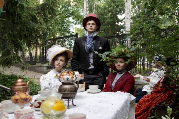 Ekaterinburg, Russia - July, 20, 2019. Retro costumes and historical reconstruction in city park. Men and Women dressed clothes 19 century. Participants of the historical reconstruction which imitates the tea ceremony in merchant houses of Russia. People gathered in the garden, drink tea, play games. Picnic in a city park..