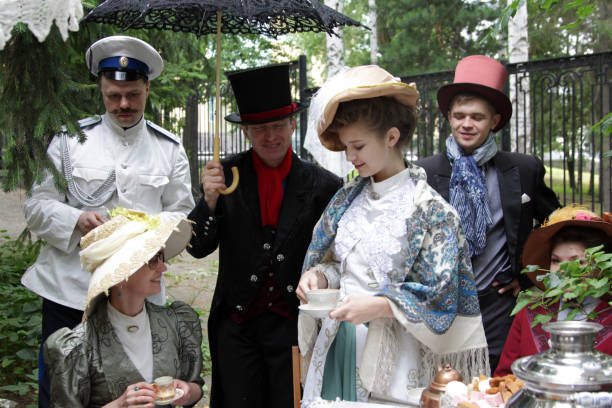 Retro costumes and historical reconstruction in city park. Men and Women dressed clothes 19 century Ekaterinburg, Russia - July, 20, 2019. Retro costumes and historical reconstruction in city park. Men and Women dressed clothes 19 century. Participants of the historical reconstruction which imitates the tea ceremony in merchant houses of Russia. People gathered in the garden, drink tea, play games. Picnic in a city park. historical reenactment stock pictures, royalty-free photos & images