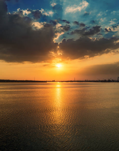istock orange sunset in dramatic clouds over water in river 1168031069