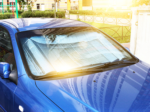 Superficie reflectante protectora bajo el parabrisas del coche de pasajeros aparcado en un día caluroso, calentado por los rayos del sol dentro del coche. photo
