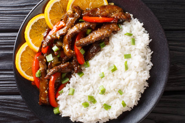 boeuf sauté asiatique avec poivron dans la sauce orange de soja servie avec le plan rapproché de riz sur une plaque. vue horizontale du haut - beef rice orange stir fried photos et images de collection