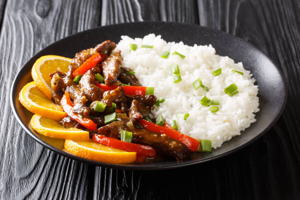 carne de res de estilo asiático con pimiento en salsa agridulce servida con arroz de cerca en un plato. horizontal - beef rice orange stir fried fotografías e imágenes de stock