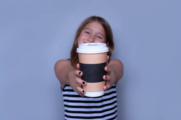 Smiling girl giving, showing coffeecup closeup side view