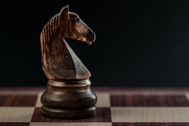 istock close view of a black chess knight alone on the chessboard, black background and copyspace 1168038418