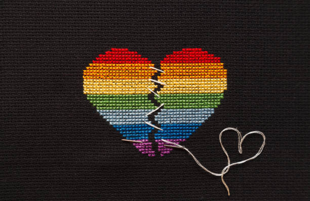 istock Broken heart embroidered on black cloth with rainbow threads. Heart sewn with white threads. 1168039269