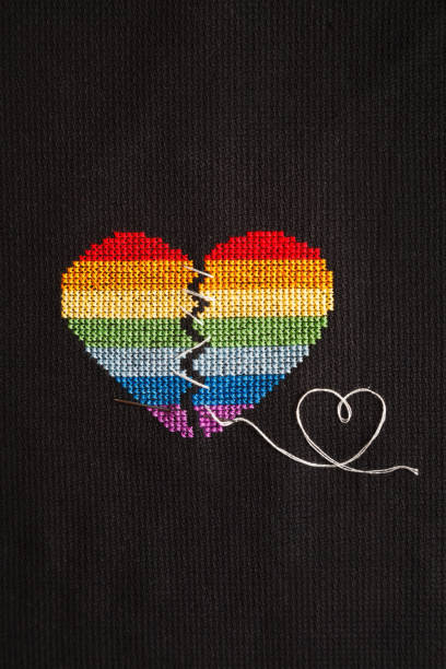 istock Broken heart embroidered on black cloth with rainbow threads. Heart sewn with white threads. 1168039271