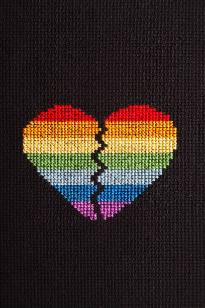 istock Broken heart embroidered on black cloth with rainbow threads. 1168039275