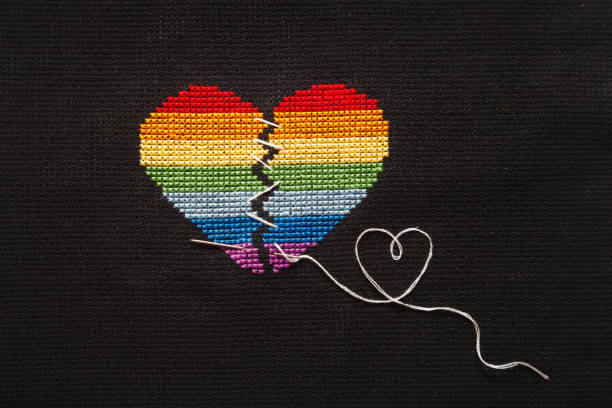 istock Broken heart embroidered on black cloth with rainbow threads. Heart sewn with white threads. 1168039276