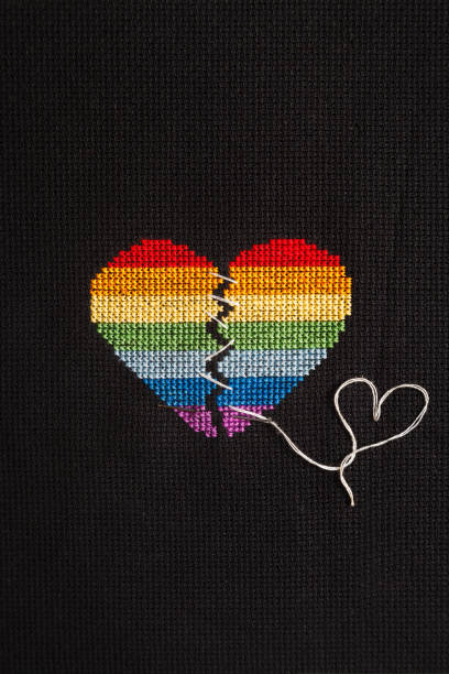 istock Broken heart embroidered on black cloth with rainbow threads. Heart sewn with white threads. 1168039277