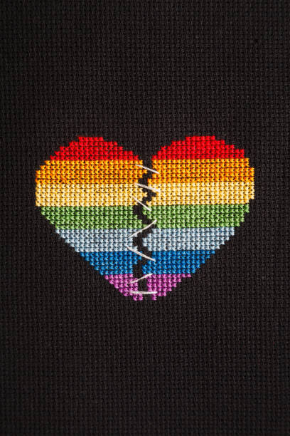 istock Broken heart embroidered on black cloth with rainbow threads. Heart sewn with white threads. 1168039278
