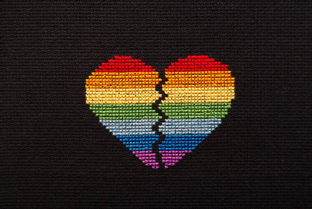 Broken heart embroidered on black cloth with rainbow threads.