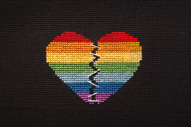 istock Broken heart embroidered on black cloth with rainbow threads. Heart sewn with white threads. 1168039280