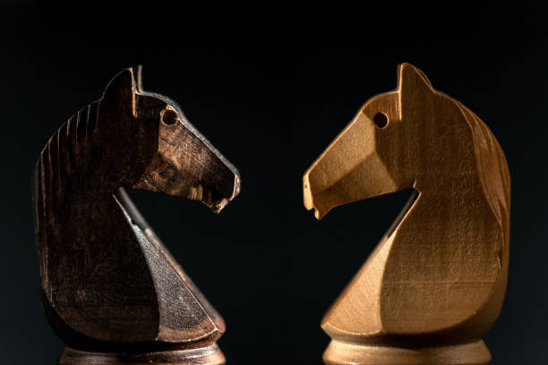 istock close view of white and black chess knights facing on blackground. 1168039587