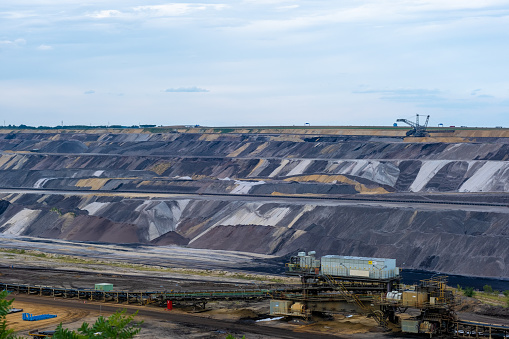 This scene shows brown coal surface mining at Garzweiler in the German state of North-Rhine Westphalia. The picture was taken on 14th of August and shows the massive mining engines, digging into the ground, under a beautiful, slightly cloudy sky.\nIt is operated by RWE and used for mining lignite. The mine currently has a size of 48 km² and got its name from the village of Garzweiler, which previously existed at this location.