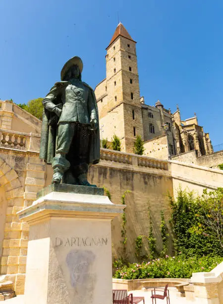 View of statue of dArtagnan dressed in his musketeer attire on background of former prison ancient Armagnac Tower, Auch, France