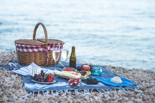istock Summer beach  romantic picnic at sunset. Seaside light evening picnic  with fresh fruit and tray of tasty appetizers,  glasses with sparkling wine 1168043634