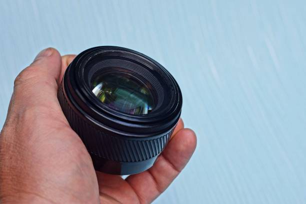 istock black open camera lens in a hand on a blue background 1168045900
