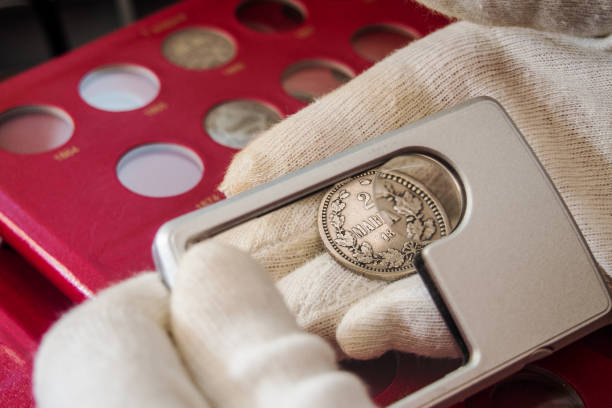Numismatist inspects old collectible Finnish coins stock photo