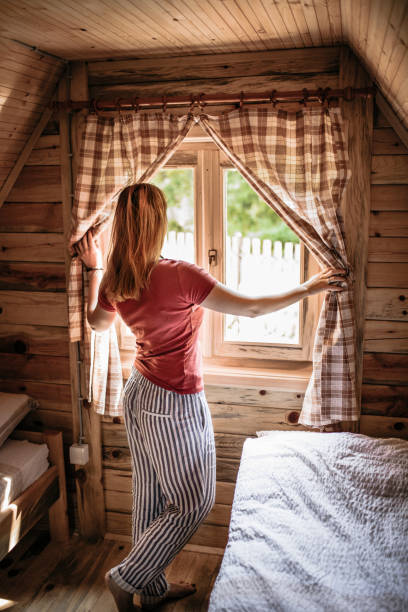 istock Woman in cozy log cabin looking through window 1168052572