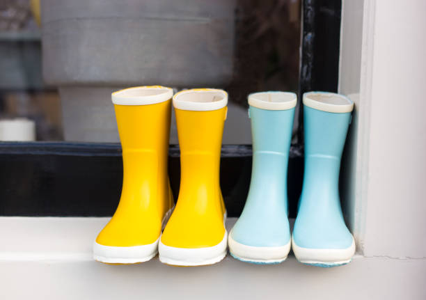 Girls’ yellow and blue rubber boots lined up on sill.