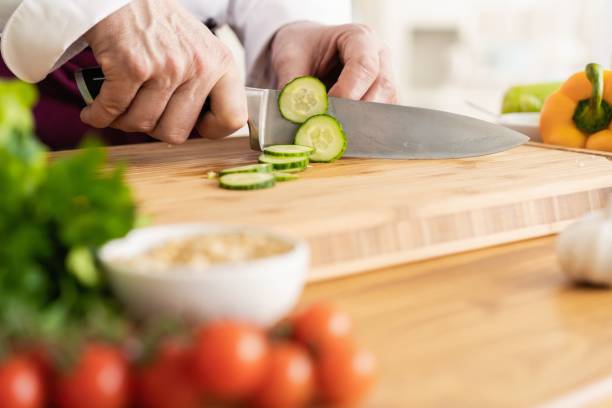 cozinheiro chefe que corta vegetais frescos e deliciosos para cozinhar. - hotel commercial kitchen organic salad - fotografias e filmes do acervo