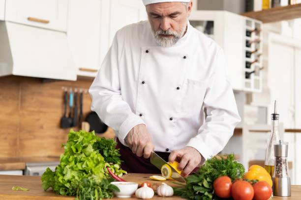 cozinheiro chefe que corta vegetais frescos e deliciosos para cozinhar. - hotel commercial kitchen organic salad - fotografias e filmes do acervo