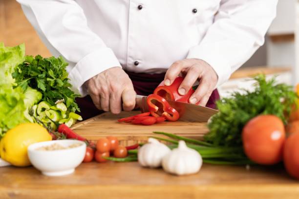 cozinheiro chefe que corta vegetais frescos e deliciosos para cozinhar. - hotel commercial kitchen organic salad - fotografias e filmes do acervo