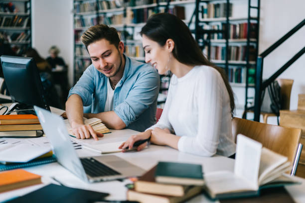 istock Male and female students cooperating on homework doing common project in college library with wifi, young woman and man talking about education spending time in campus doing homework at desktop 1168056812
