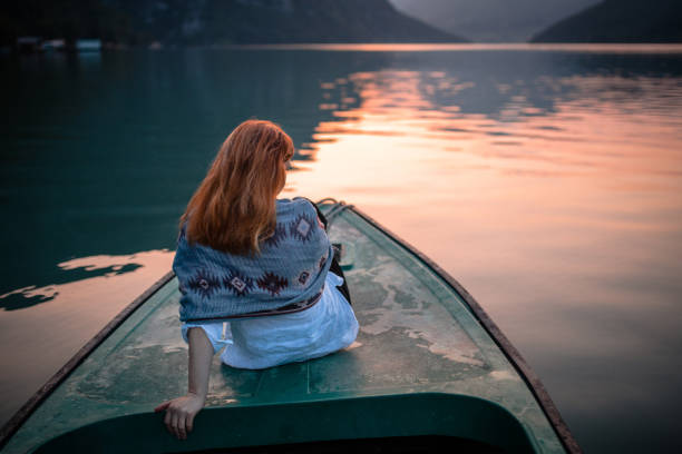 istock Woman sitting on boat prow in sunset 1168059611