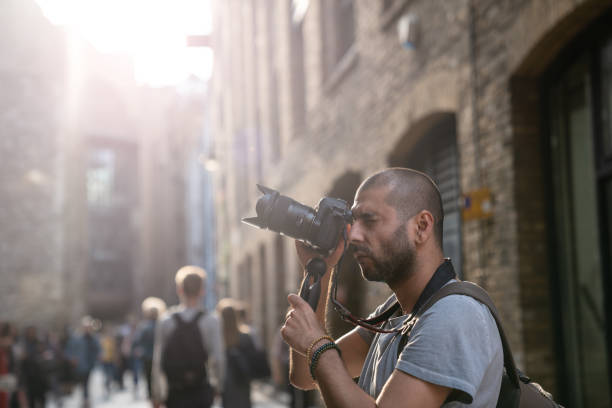 Portrait of Street photographer In City Of London Portraits of adult photographer photographing streets of city of London. Architectural style of city is seen on the background.  He is in casual clothings and has short hair. Selective focus on model while large group of people are seen blurred. Shot under daylight with a full frame mirrorless digital camera. borough market stock pictures, royalty-free photos & images
