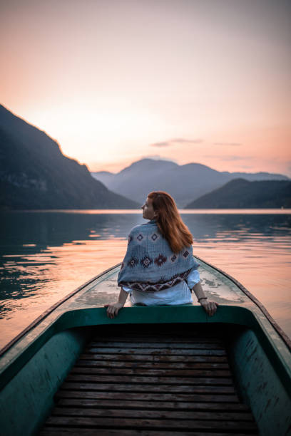 istock Woman sitting on boat prow in sunset 1168060456