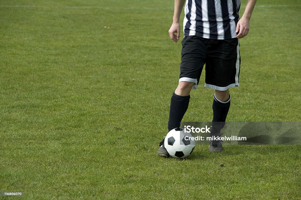 Giocatore di calcio dribbling in un campo di calcio - Foto stock royalty-free di Abbigliamento sportivo