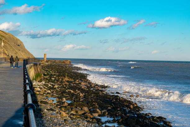 istock Couple walking down sunny sands promenade in Folkestone kent 1168060731