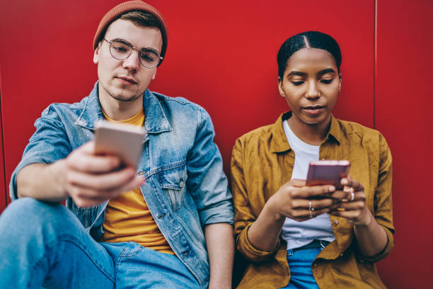trendy dressed multiracial hipster girl and guy sitting together ignore real communication prefere to chatting in social networks via modern smartphones and 4g internet connection, addiction to phone - hipster people surfing the net internet imagens e fotografias de stock