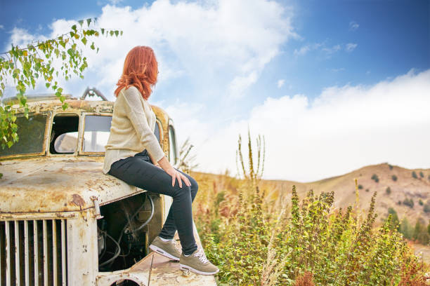 istock Woman sitting on rusty old classic truck. 1168064144