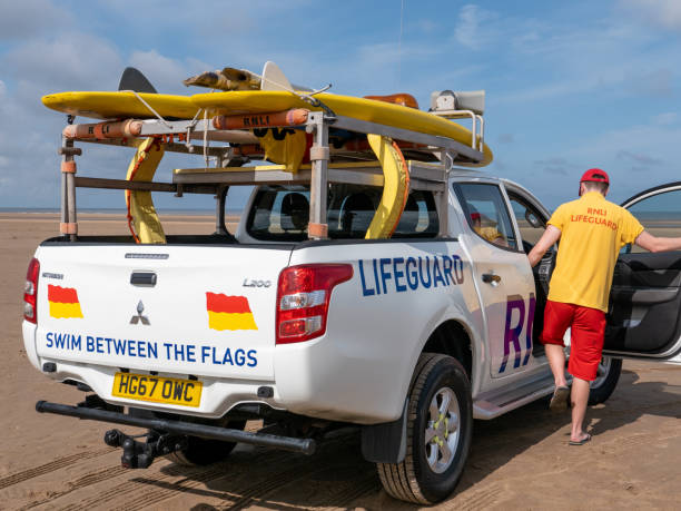 a rnli lifeguard getting into his rescue vehicle to patrol a beach - lifeguard association imagens e fotografias de stock