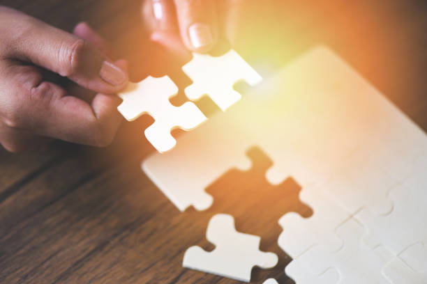 istock jigsaw puzzle with woman hand connecting jigsaw piece with sunlight - Business solutions partnership success and strategy concept 1168073608