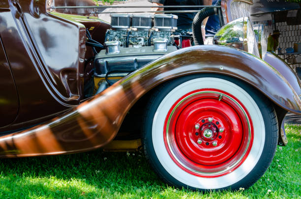 Side view of the engine, three carburetors and front red wheels of a antique restored brown hot rod Side view of the engine, three carburetors and front red wheels of a antique restored brown hot rod cruising hot rods stock pictures, royalty-free photos & images