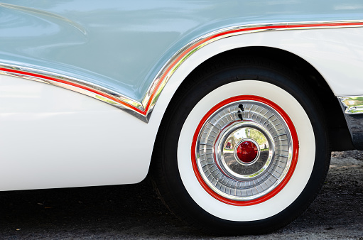 Close-up of a geometric pinstripe on chrome trim and matching coloring on a vintage car's wheel