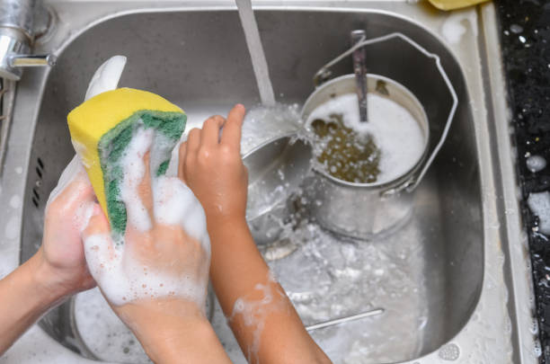 istock kids washing dishware in the kitchen sink with soapy sponge 1168076452