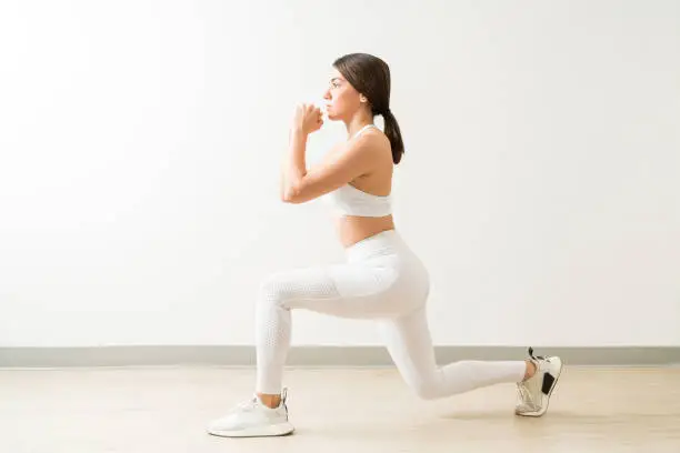 Confident young attractive fit woman doing low lunge exercise at yoga studio