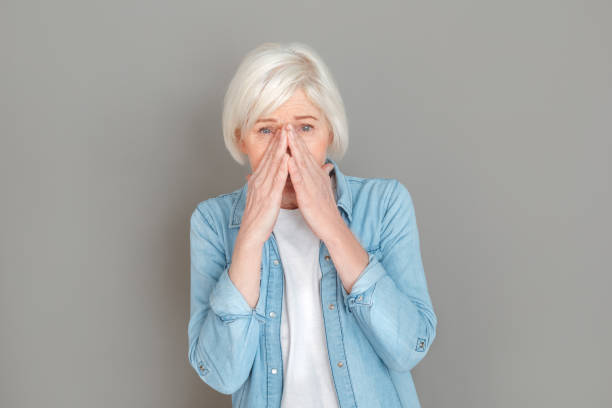 istock Senior woman in jeans jacket studio isolated on grey wall sneezing 1168079905