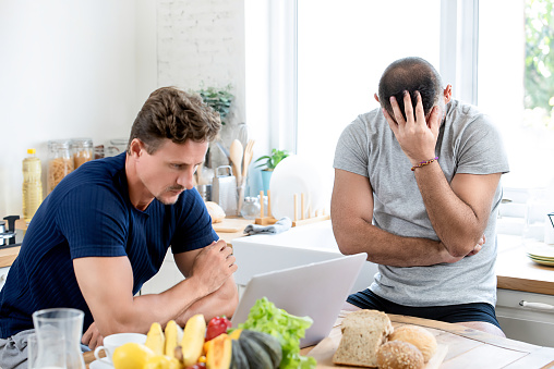 Married gay male couple being angry with each other after having conflict in kitchen at home,  LGBT life concept