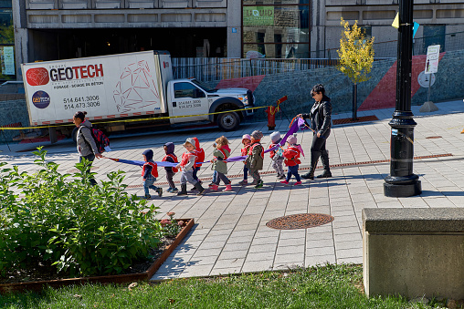 Montreal, Quebec, Canada, September 14, 2018: Teachers with young children from kindergarten stroll around the university yard. Living a happy lifestyle while traveling in Canada.