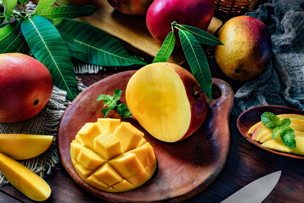 istock Tropical Fruits: Sliced mangos in a clay rustic plate on a wooden table in rustic kitchen 1168090690