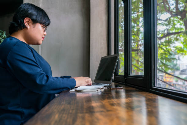 Student using laptop next to window with beautiful garden view Asian student using laptop next to window with beautiful garden view lgbtqcollection stock pictures, royalty-free photos & images