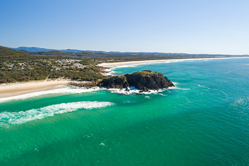 Aerial of headland on the coast with inviting water, sunrise, blue water for swimming and surfing. Family or retiree destination in summer holiday. Cabarita Beach in Queensland
