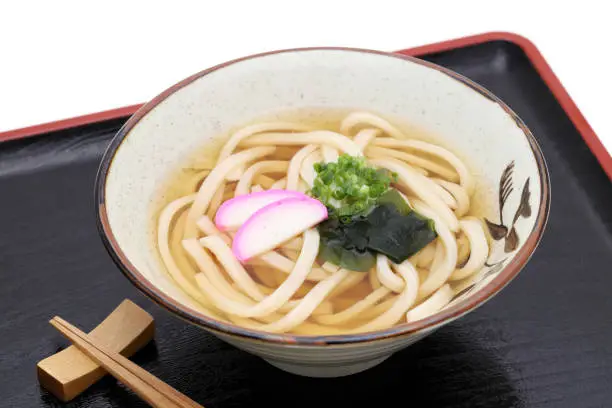 Japanese Kake udon noodles in a ceramic bowl on white background