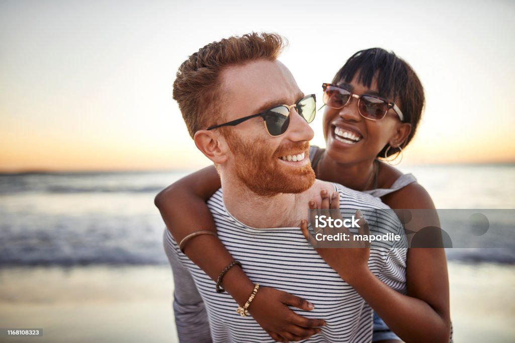 The ocean brings everyone closer together Shot of a happy young couple spending the day at the beach Couple - Relationship Stock Photo
