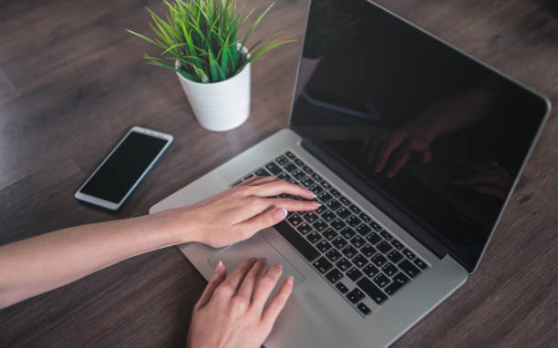 istock Woman uses a laptop with blank black screen. Template for your Mockup. 1168113297